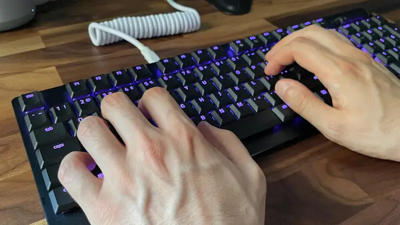 A person types on a gaming keyboard.