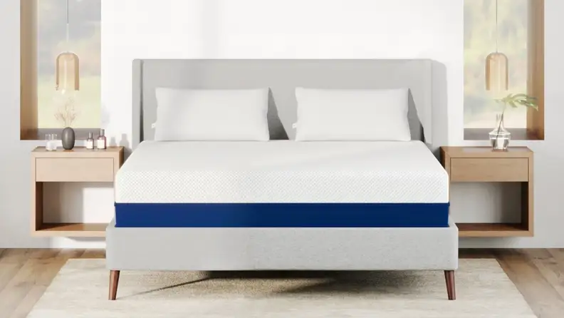 merisleep AS3 memory foam mattress with white cover and blue base on a gray upholstered bed frame in a bright modern bedroom.