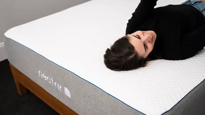 a woman lies on her back on the Nectar mattress