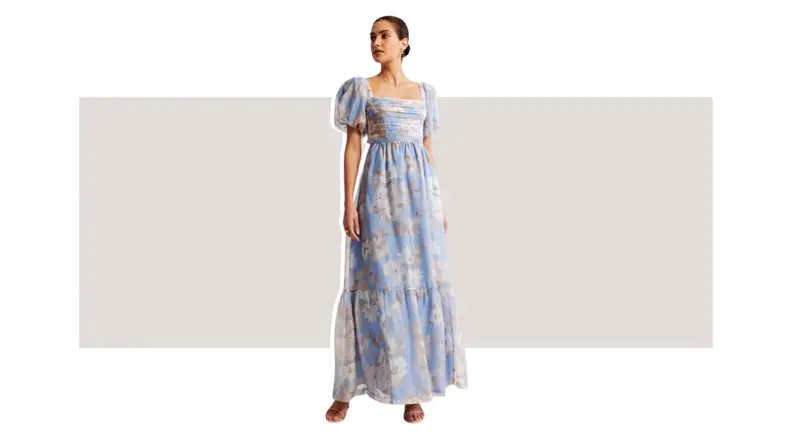 A model wearing a blue floral chiffon gown with puffed sleeves.