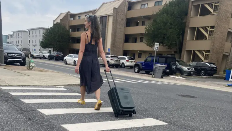 Woman walking in a crosswalk with a Coolife suitcase.