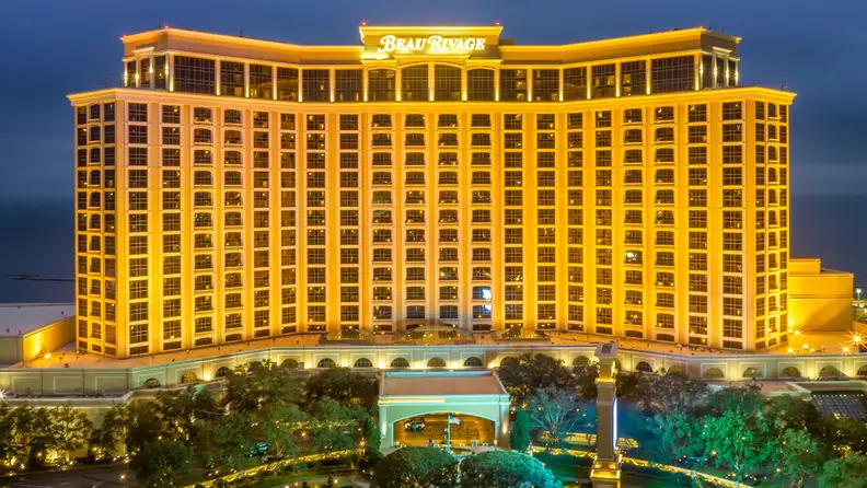 Beau Rivage Resort & Casino in Biloxi, Mississippi illuminated at night with its signature golden exterior overlooking the Gulf Coast.