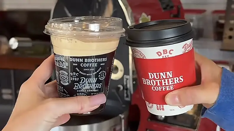 Two hands holding iced and hot coffee cups together
