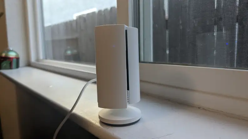 The second-gen Ring Indoor Cam with solid, white privacy screen covering camera while sitting on window sill in front of closed window.