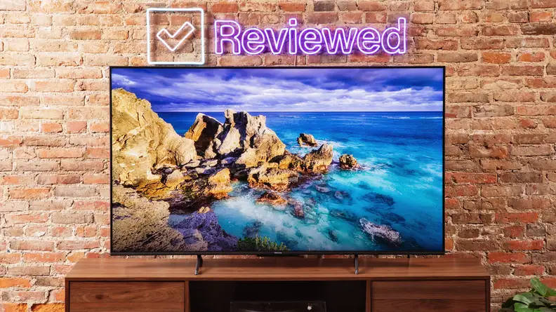 The Hisense U6K Mini-LED TV on a table with a brick background.