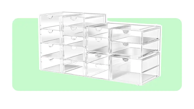 Multiple stacked empty clear storage bins in front of light green background.