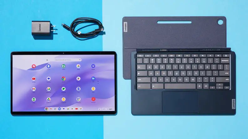 The Lenovo IdeaPad Duet 5 detached from the black keyboard, side-by-side, and the charging block and cord is above the IdeaPad screen.