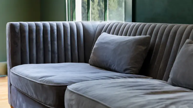 A grey couch in a dark green room