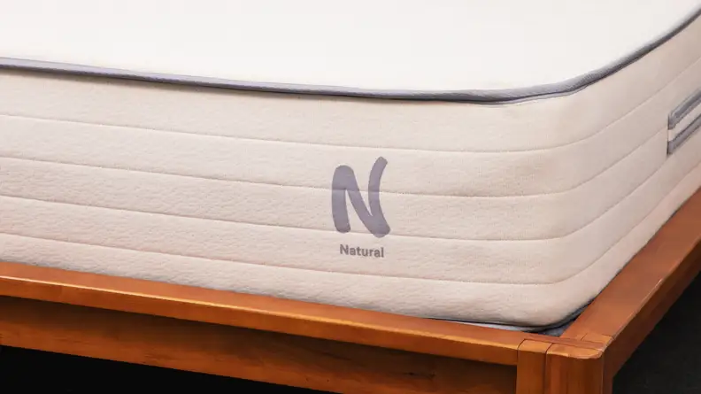 A closer look at the bottom corner of the Nolah Natural mattress inside of a bed frame.