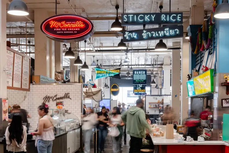 Neon food stall signs inside a bustling Grand Central Market