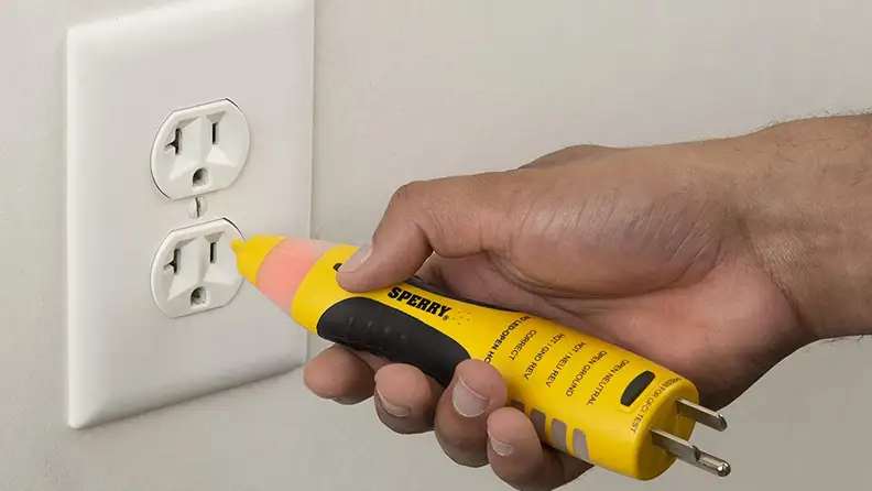 A person tests an electrical outlet.
