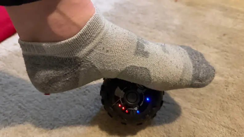 A foot stands on a black ball