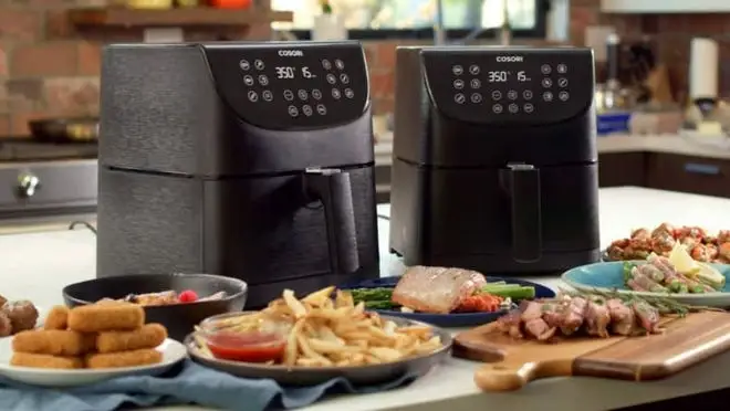 two Cosori air fryers sitting behind plates full of food