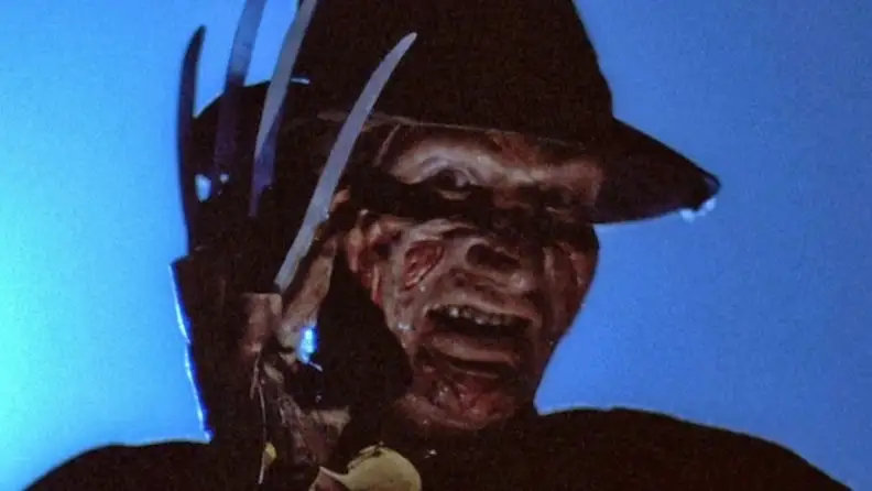 A close-up of Freddy Krueger, with bladed glove partially covering his face, from "A Nightmare on Elm Street."