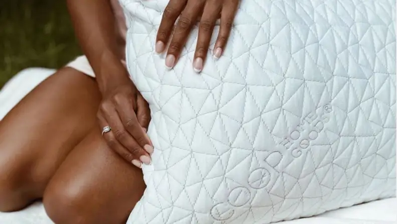 a woman sits on bed with the Coop Home Goods Original Pillow