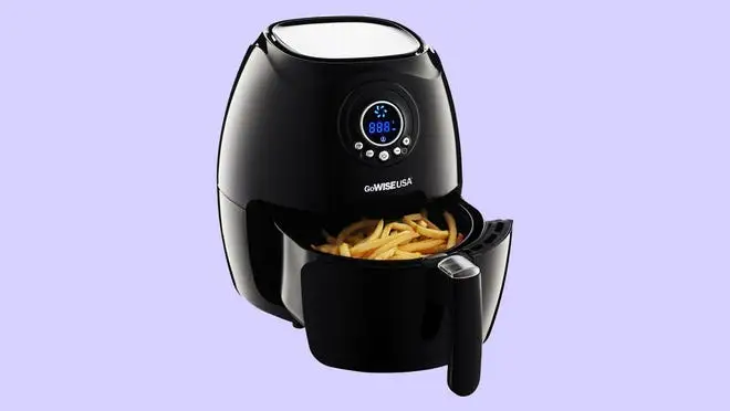 Black air fryer with french fries inside.