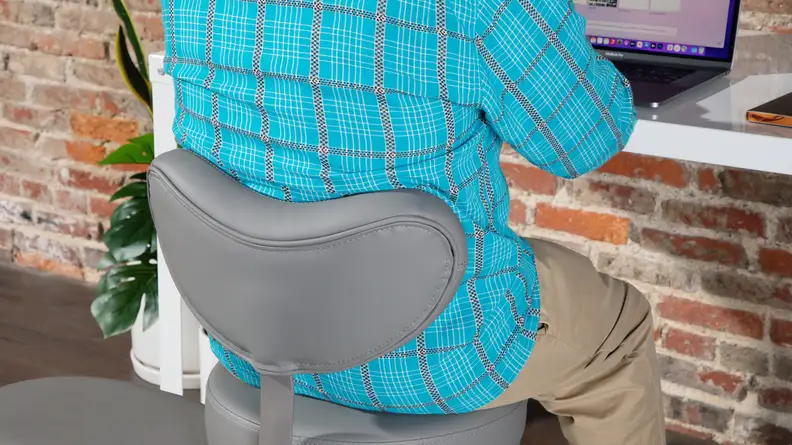 Person sitting upright in Pipersong Meditation Chair while working at desk on laptop computer .