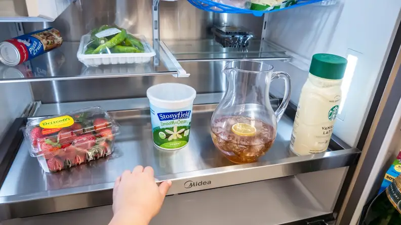 Person pulling out the full-width glide-out tray inside of fridge.