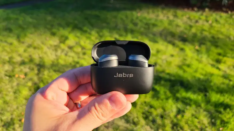 Close up a persons hand holding the charging case of the Jabra Elite 85t earbuds.