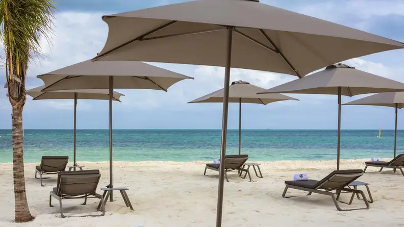 A photograph of a beach in Mexico with four beach umbrellas open