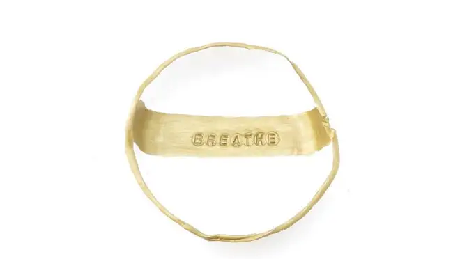 A white and gold jewelry dish that says "breathe."