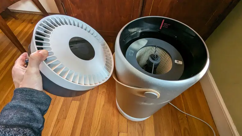 A man opens the top of the Molekule air purifier.