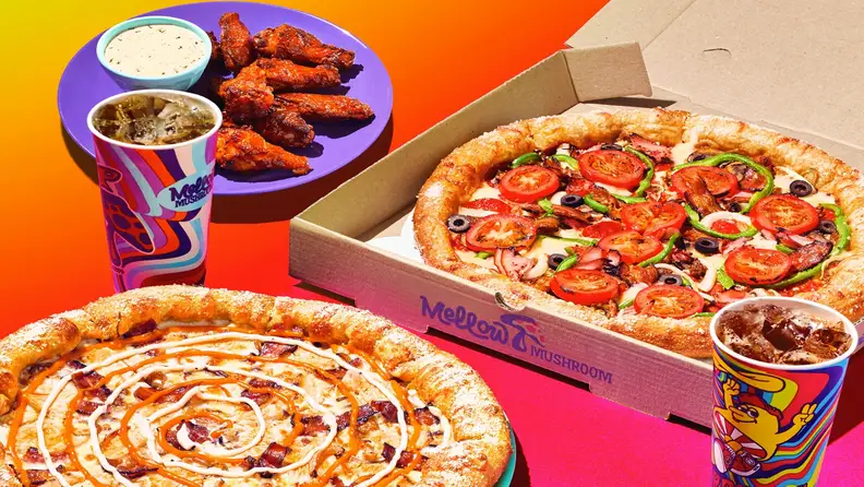 An assortment of Mellow Mushroom pizzas, wings, and drinks