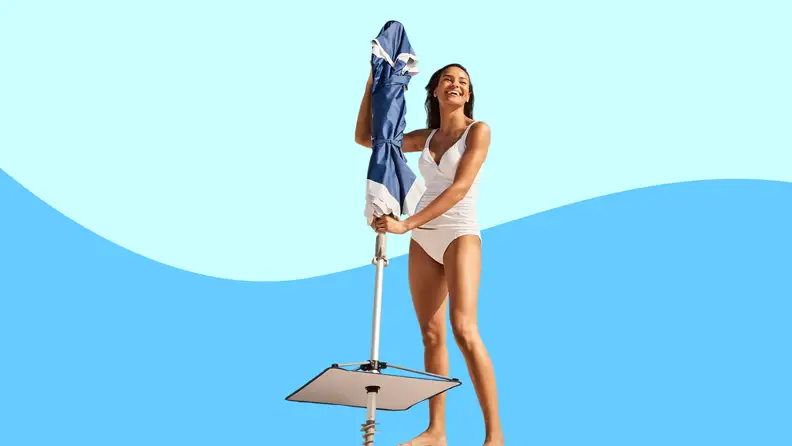 Woman holding a folded Tommy Bahama beach umbrella on colored background