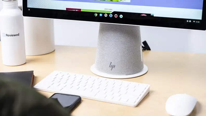A wireless keyboard and mouse sit in front of the computer base