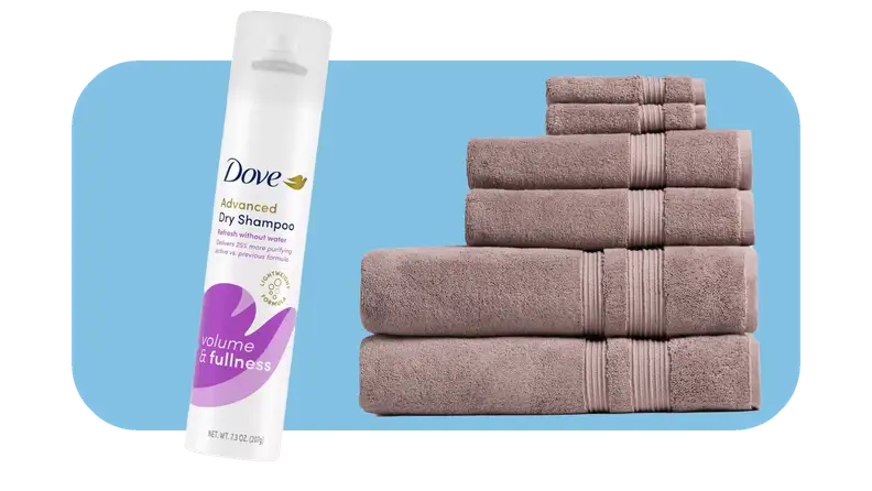 Purple and white can of dry shampoo next to plum colored stack of towels.
