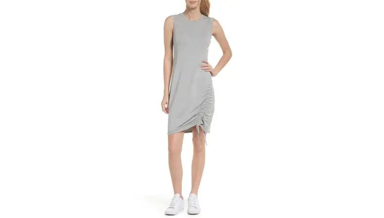 A model wearing a tight, knit grey dress with white sneakers to accessorize.