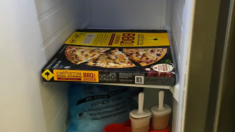 A shot of a standard 12" pizza box crammed onto the 12"-wide freezer shelf of the Samsung RS27T5200SR side-by-side refrigerator.