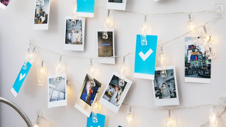 Polaroid photos clipped to string lights in a dorm room.