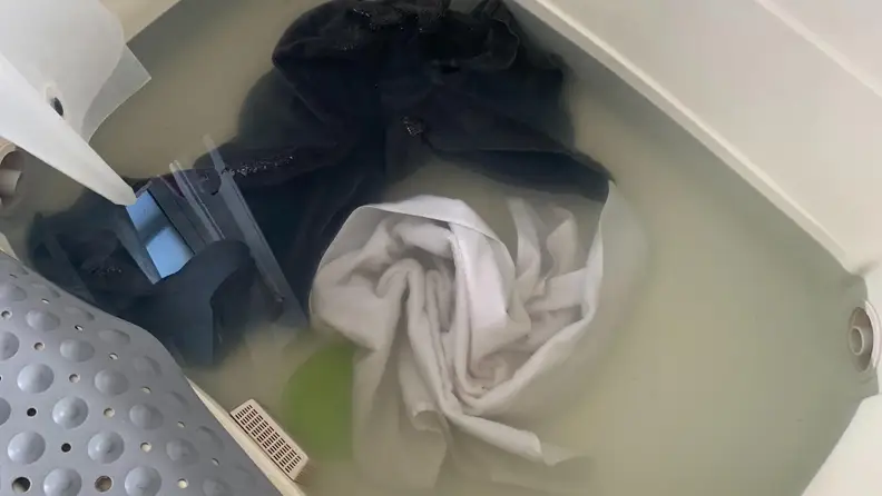 One dark towel and one light towel soaking in mixture of borax, washing soda, and laundry detergent for four hours
