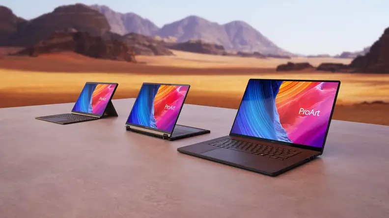 Three Asus ProArt laptops, the P16, PX13, and PZ13, sitting on a table out on a plain with mountains in the background.