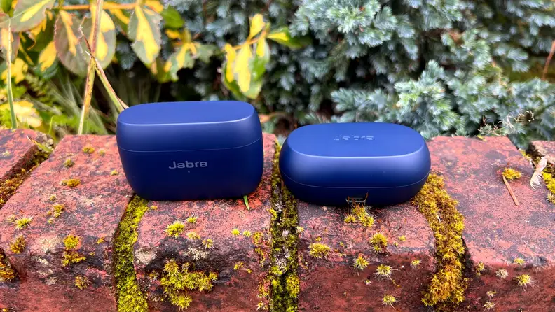 The Elite 4 Active and Elite 7 Active earbuds sit in navy cases closed on a mossy brick ledge.