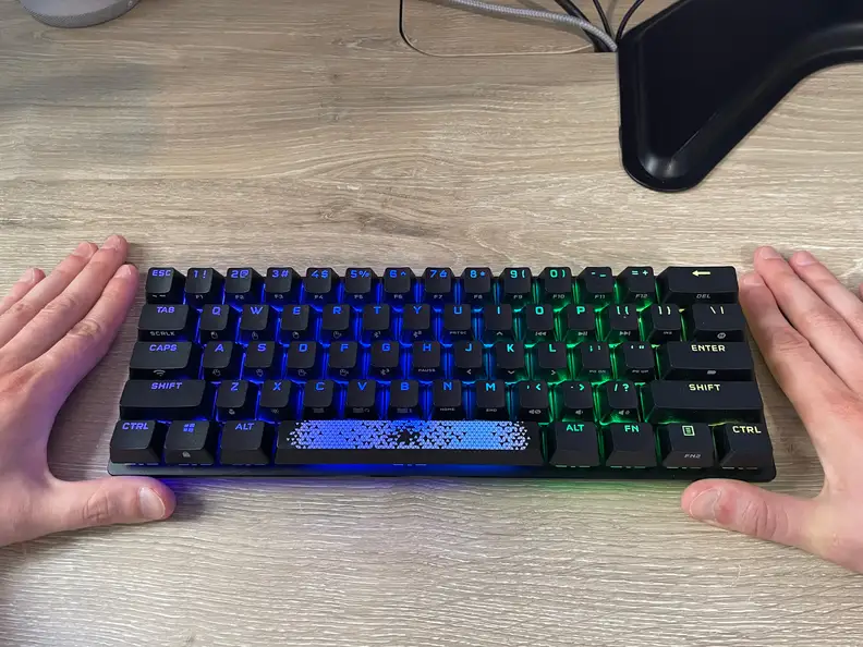 Two hands frame as small black keyboard for scale.