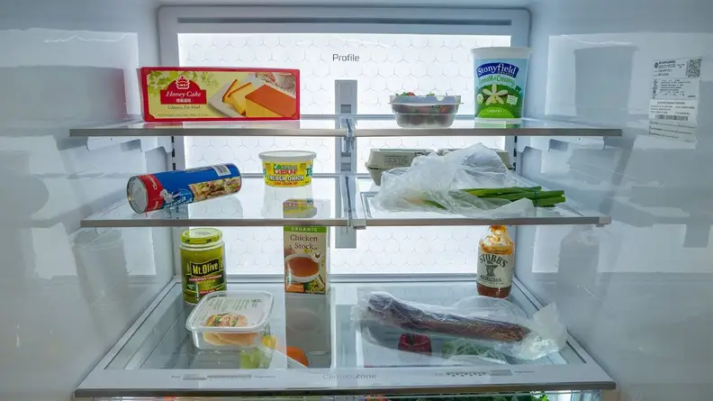 A close-up of the fridge compartment, stocked with items, all illuminated by the LED backlighting.