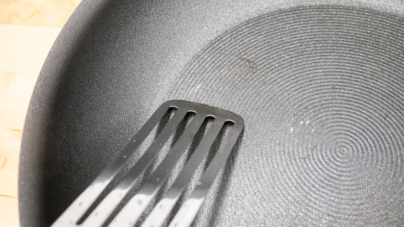 A metal thin spatula scraping the Circulon ScratchDefense Nonstick Frying Pan.