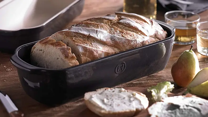 A loaf of fresh bread is served in an Emile Henry Italian bread baker.