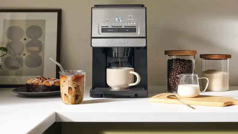 Cuisinart coffee maker brewing into a mug beside iced coffee and a pastry