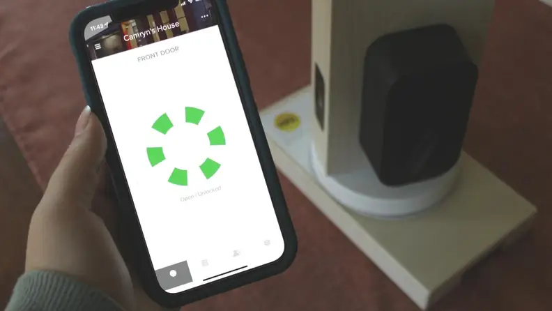 A hand holding a phone with an app displayed to unlock and lock a smart lock
