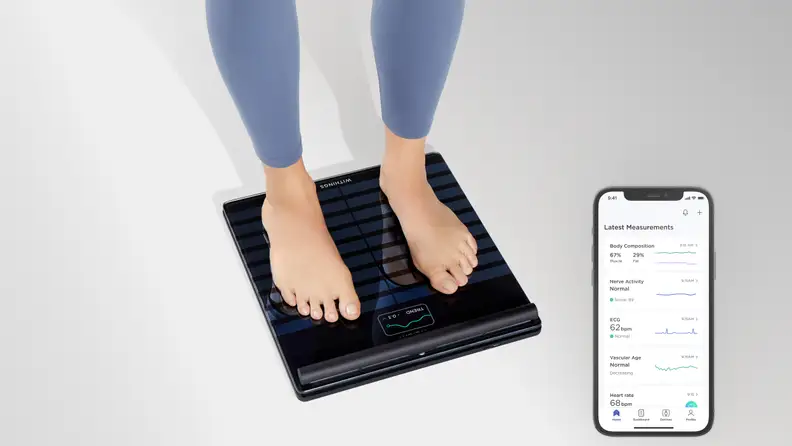 A woman standing on the Withings Body Scan.
