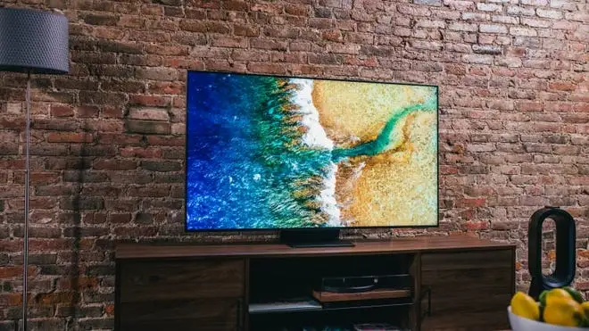 Flat screen TV in front of brick wall indoors.