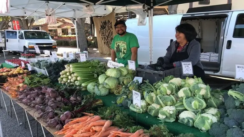 Farmers smiling behind a table of fresh vegetables