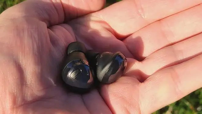 A person holds a pair of wireless headphones in their hand.