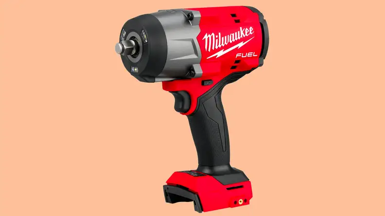 A close-up of the Milwaukee torque impact wrench on a peach-colored background.
