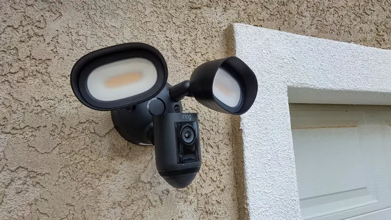 The Ring Floodlight Cam hanging on a home next to a garage door