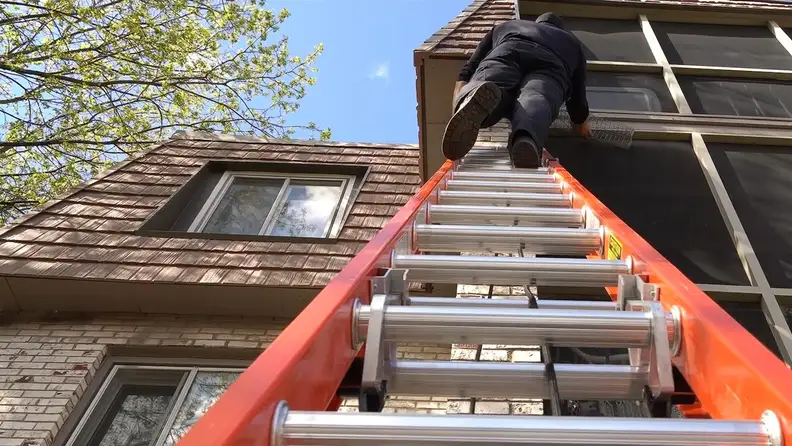 Technician climbing a ladder to inspect a home's upper level