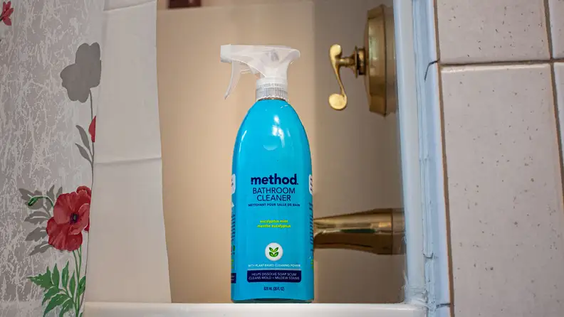 The Method cleaner stands on the edge of a tub's lip.